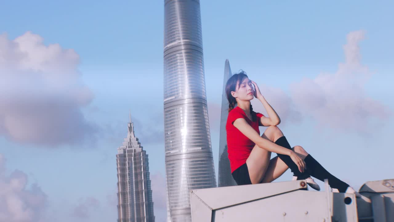 一个美丽的亚洲芭蕾舞女坐在屋顶上，向前看视频下载