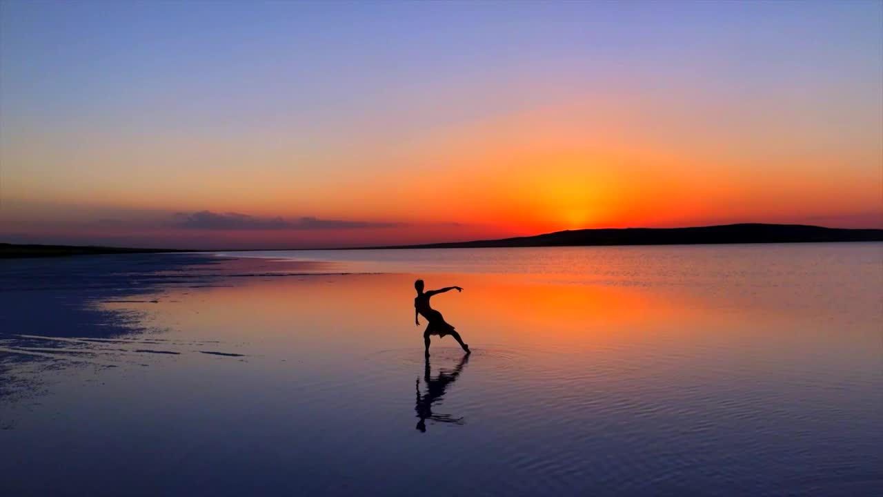 年轻的芭蕾舞演员，日落时在湖面上跳舞。视频下载