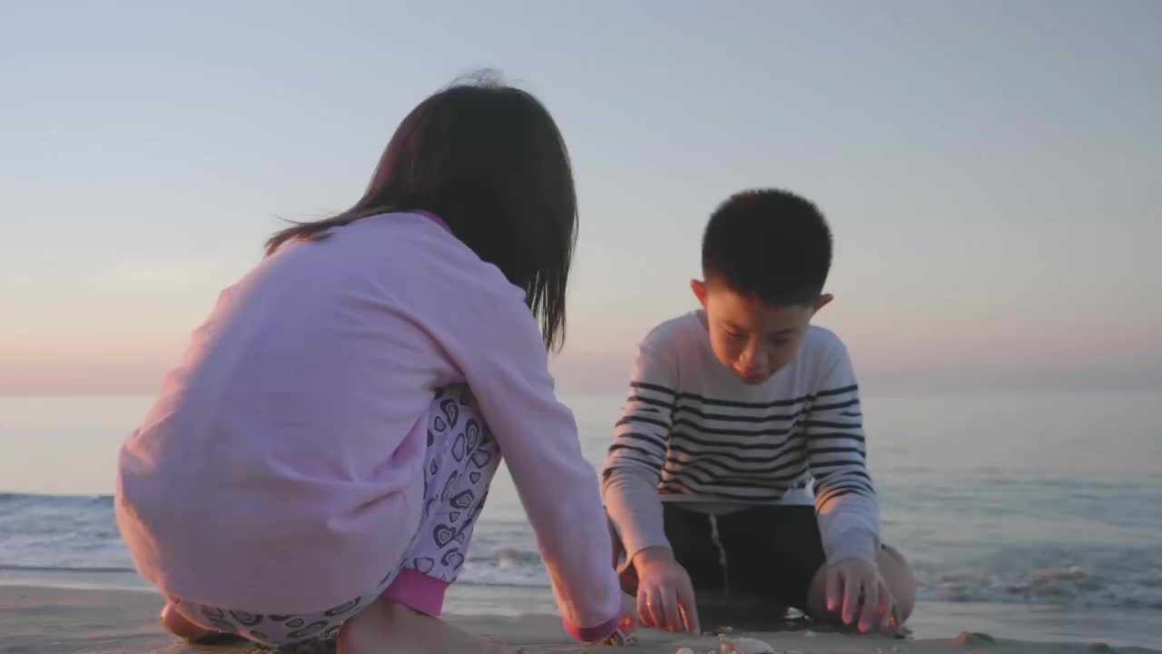 亚洲的孩子们在沙滩上玩着捡贝壳的游戏视频素材