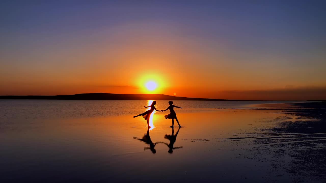 年轻的芭蕾舞演员，日落时在湖面上跳舞。视频素材