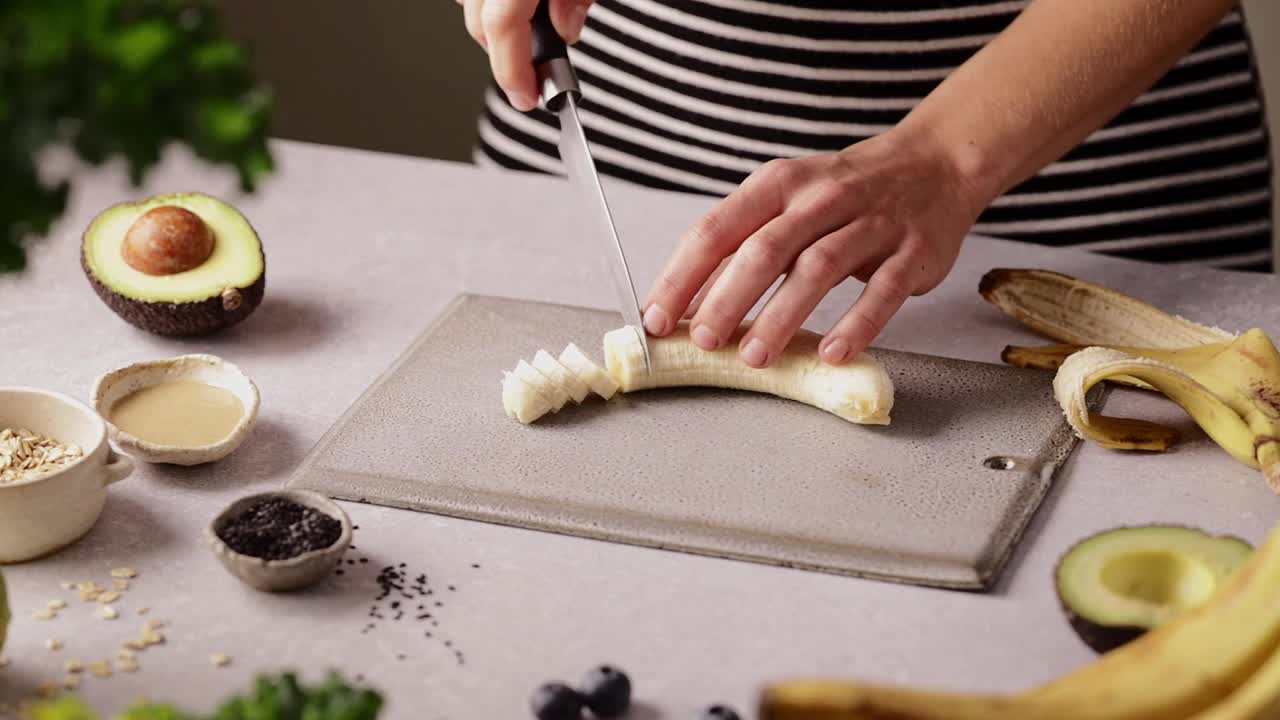 在厨房切香蕉做水果冰沙碗的女人视频下载