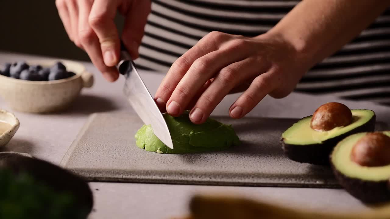 一个女人在厨房柜台上的菜板上切鳄梨的特写镜头视频下载