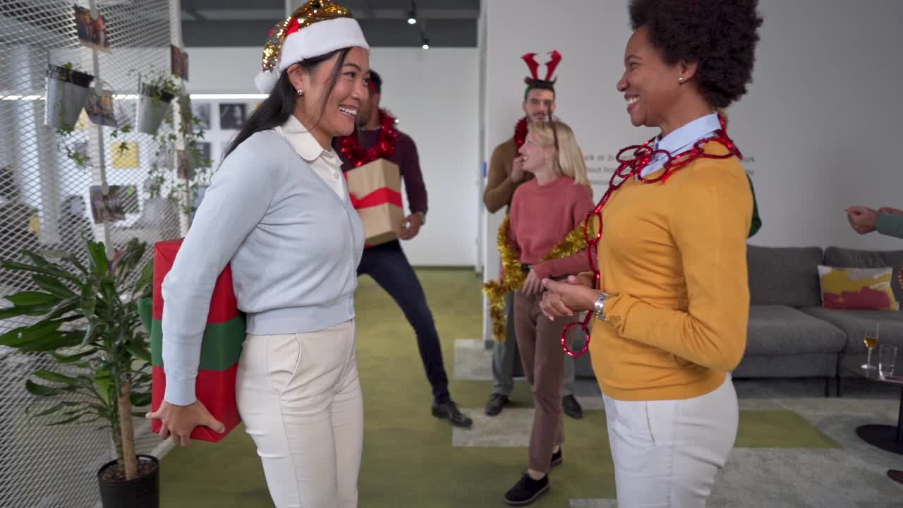 亚洲和非洲裔的商业女性在办公室享受圣诞派对视频下载