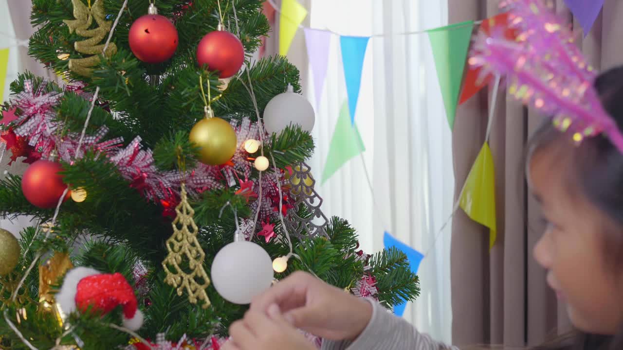 女儿正在装饰圣诞树，享受圣诞节的时光视频素材