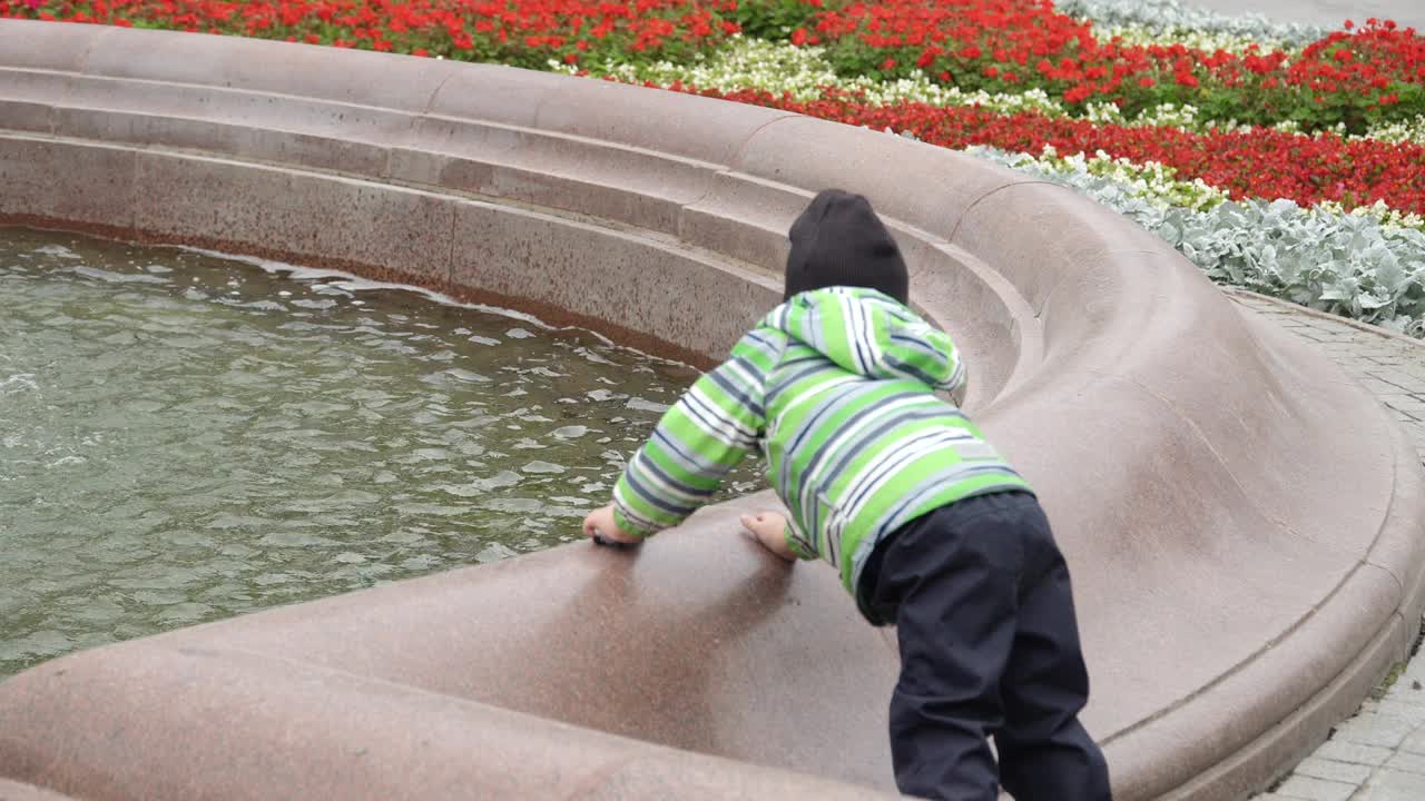一个小男孩在喷泉旁视频素材
