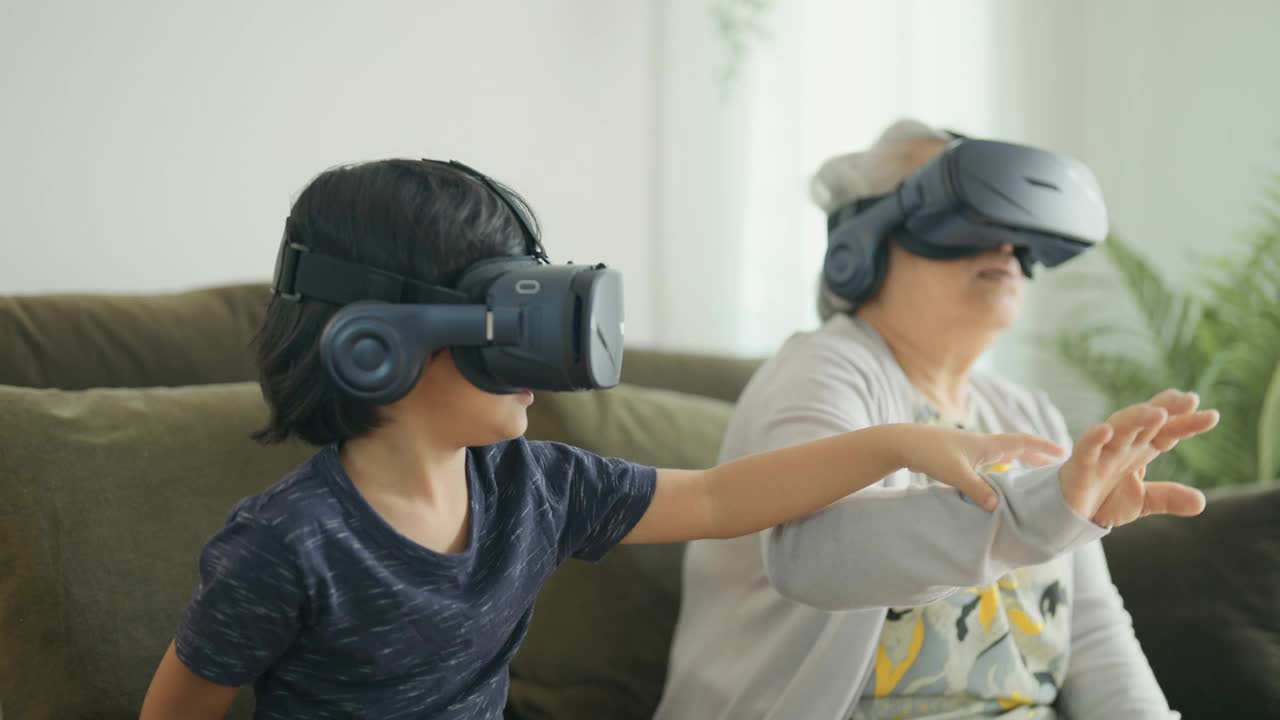 孙子和祖母在玩虚拟现实头盔。视频下载