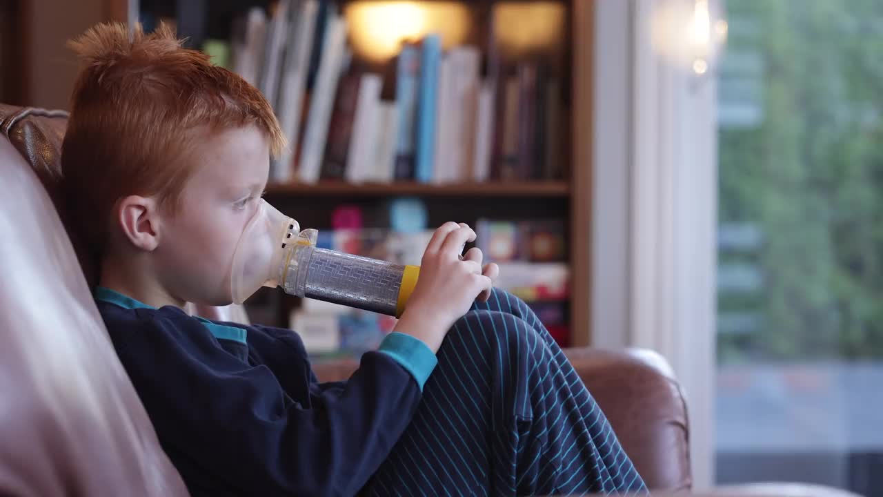小红发男孩正在用哮喘吸入器治疗呼吸性哮喘视频素材
