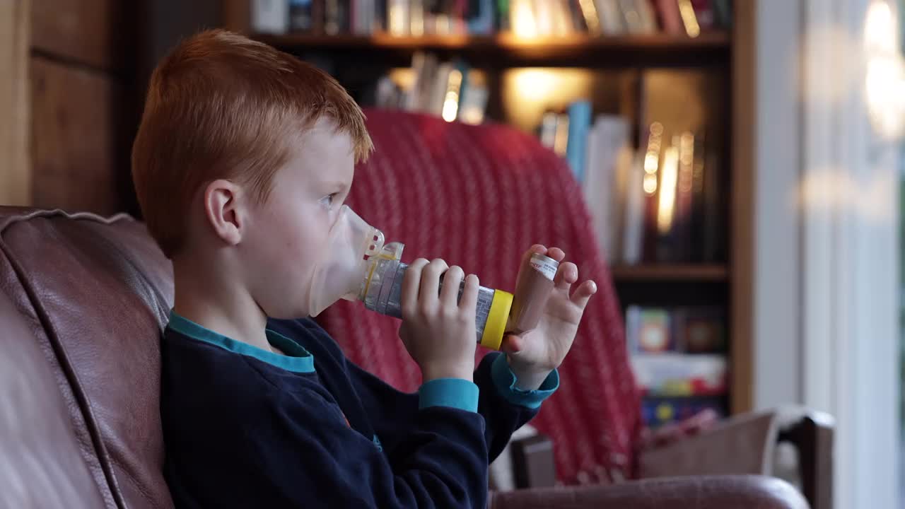 小红发男孩正在用哮喘吸入器治疗呼吸性哮喘视频素材