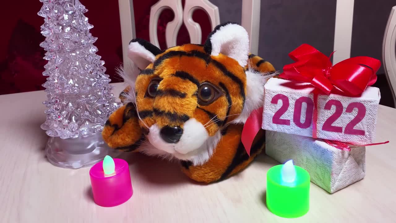 在复古房间的圣诞树旁的白色桌子上放着2022年新年的老虎标志和带有2022字样的礼盒。视频下载