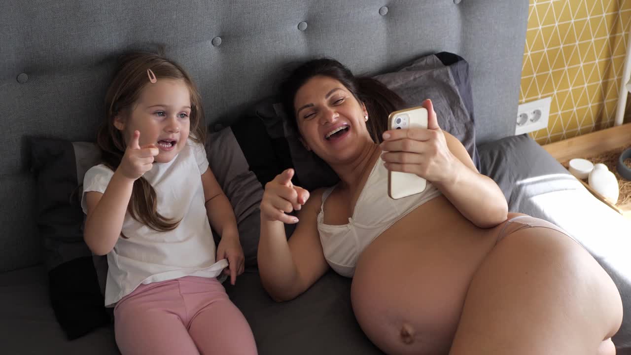 怀孕的中年妇女和女儿在家里打电话视频下载