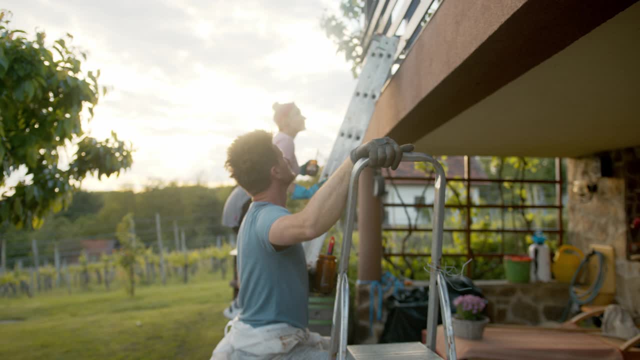 在乡下，一对夫妇正在给他们的房子刷篱笆视频素材