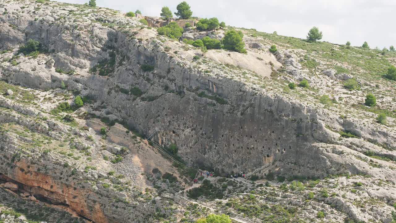 在西班牙博cairent的Cuevas de los Moros，一群游客正在参观挖掘在岩石内部的洞穴(摩尔洞穴)。视频下载