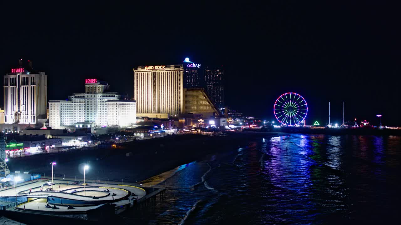 大西洋城市中心的海滨木板路，是美国东海岸著名的赌博中心，有多个赌场和码头上有摩天轮的游乐园。航拍视频与后向摄像机运动。视频下载