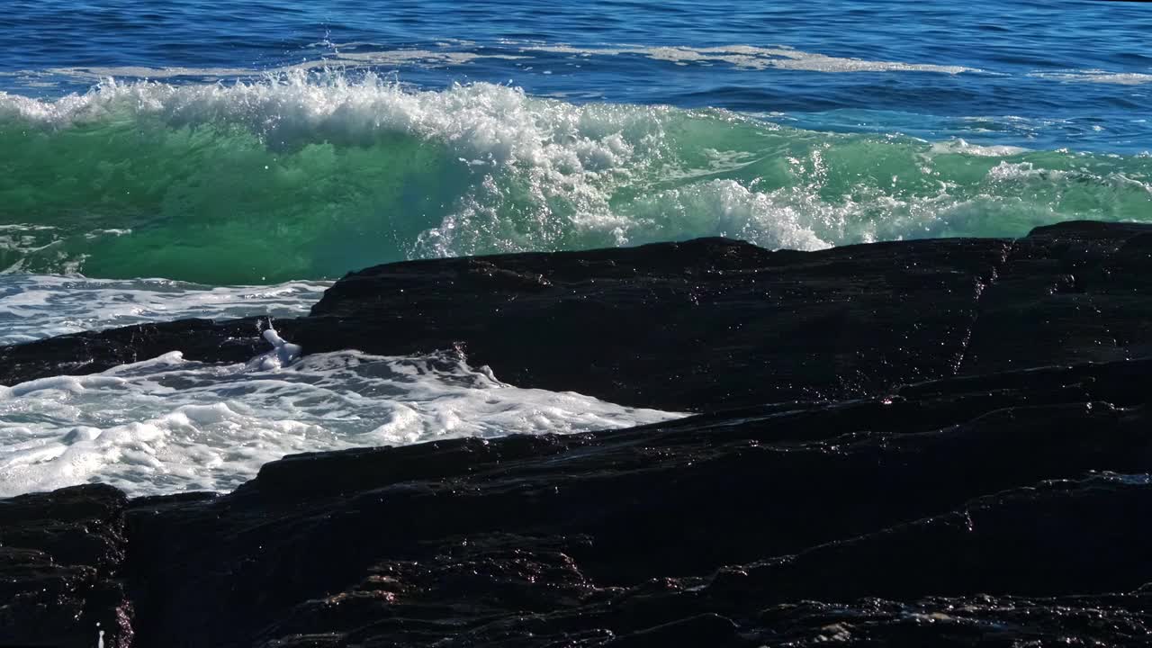 海浪冲击岩石和海滩卵石的正面视图视频下载
