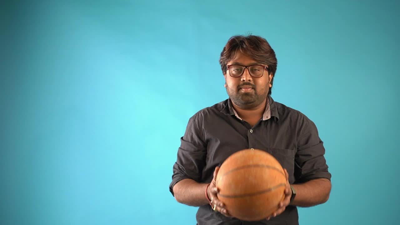 一个有趣的印度小男孩在一个孤立的蓝色背景下玩篮球视频下载