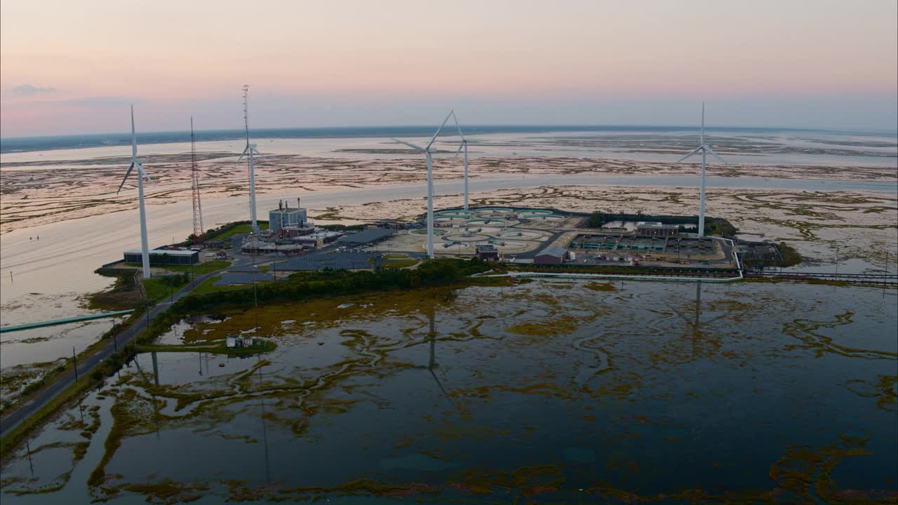 可持续能源用于环境保护。美国新泽西州大西洋城附近的一个由风力涡轮机和太阳能板供电的污水处理厂。航拍视频与前进和倾斜下的电影摄影机运动。视频下载