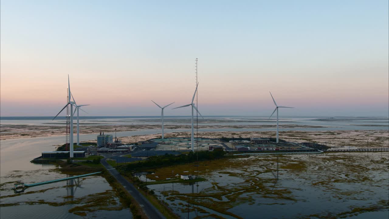 可持续能源用于环境保护。美国新泽西州大西洋城附近的一个由风力涡轮机和太阳能板供电的污水处理厂。航拍视频与后退摄像机运动。视频下载