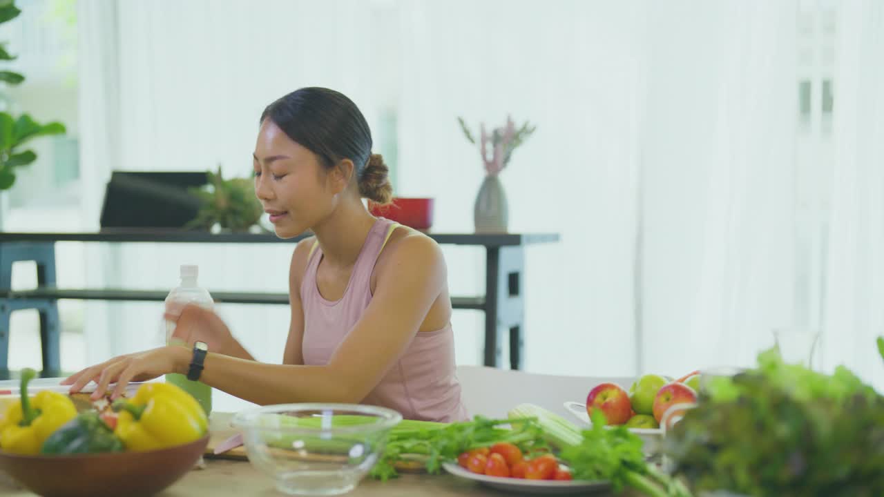 家庭主妇拿着新鲜的蔬菜和厨房工具在桌上阅读烹饪书视频下载