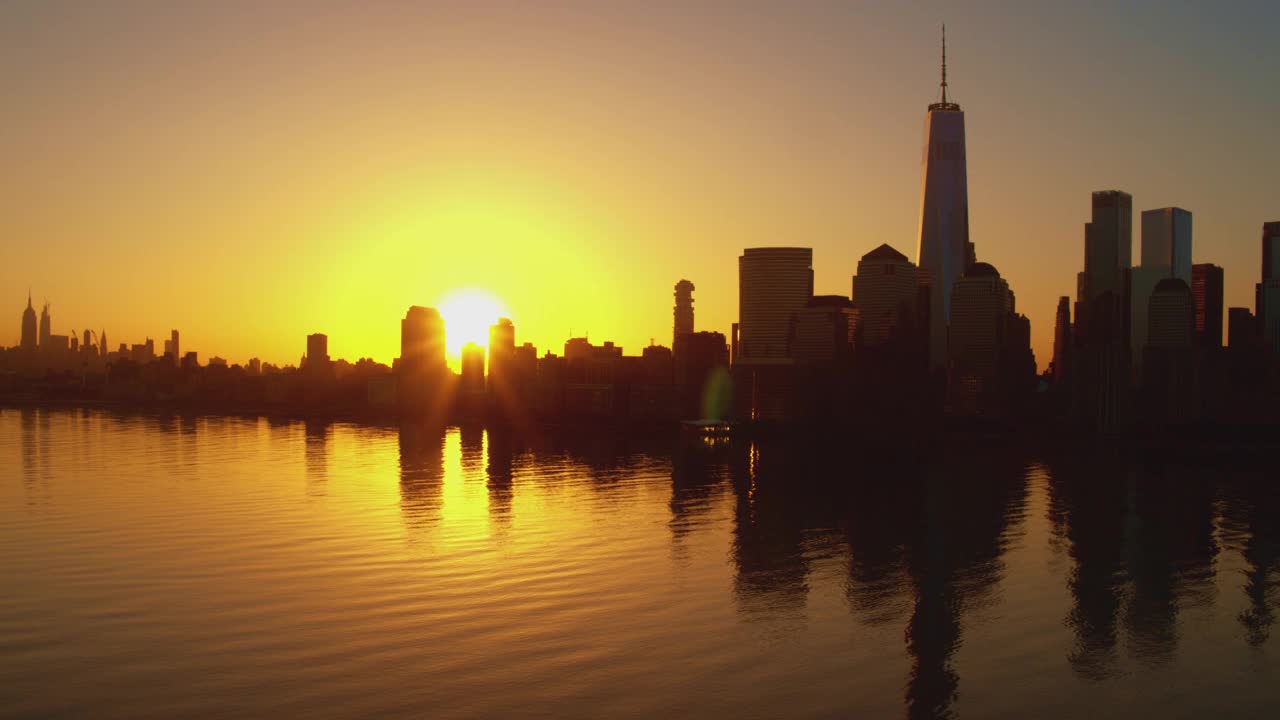 日出时分，从泽西城眺望哈德逊河对岸的曼哈顿美景。航拍镜头与电影复杂的向后平移相机运动。视频素材