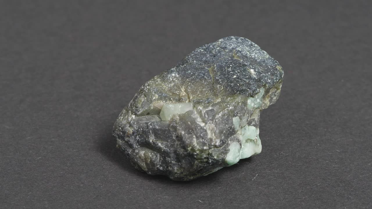 岩石中的翡翠，黑色背景上的绿柱石矿物。视频下载