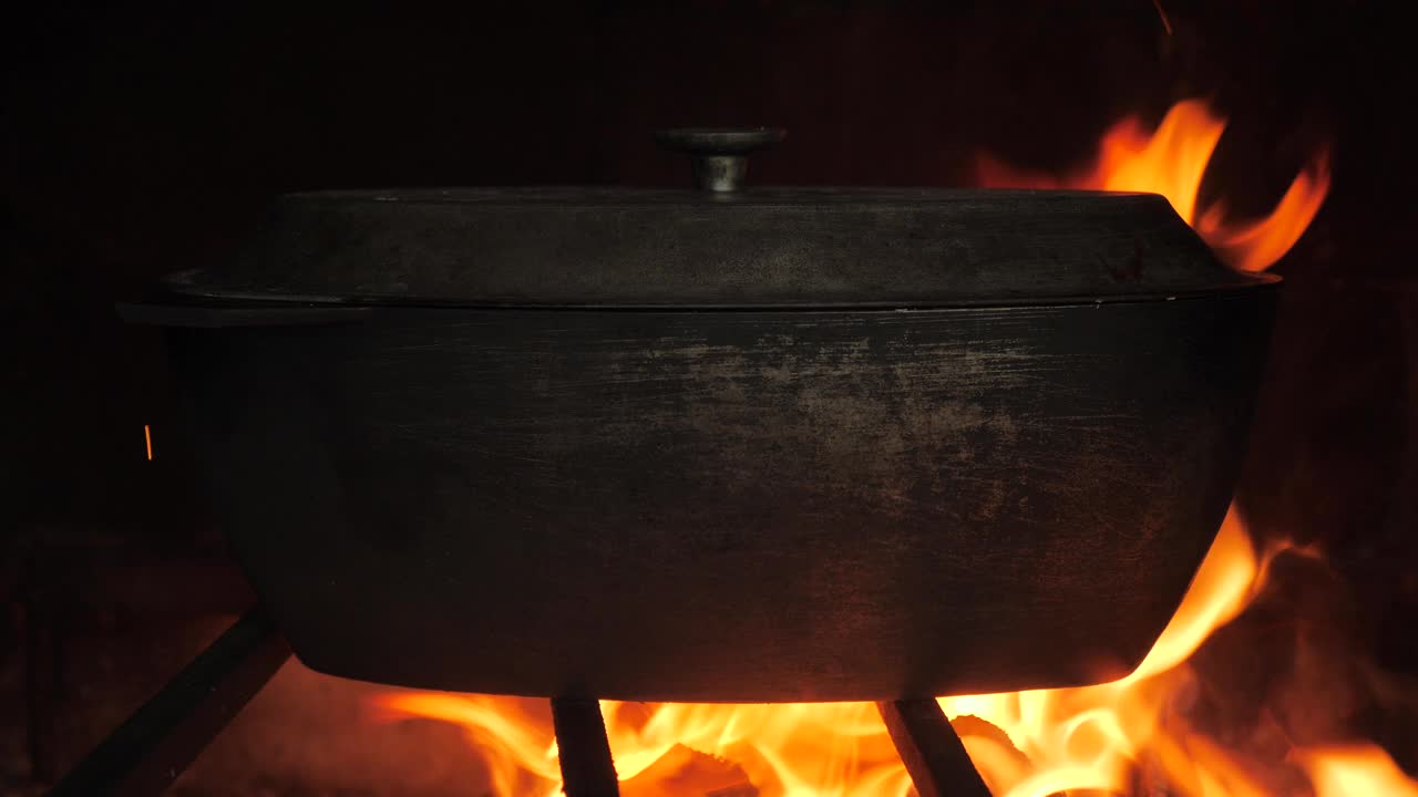传统的壁炉柴火烤炉烹饪概念。节日食物火做饭锅柴火。节日晚餐。在火上准备食物铸铁锅烧柴火，石炉烧制背景视频下载