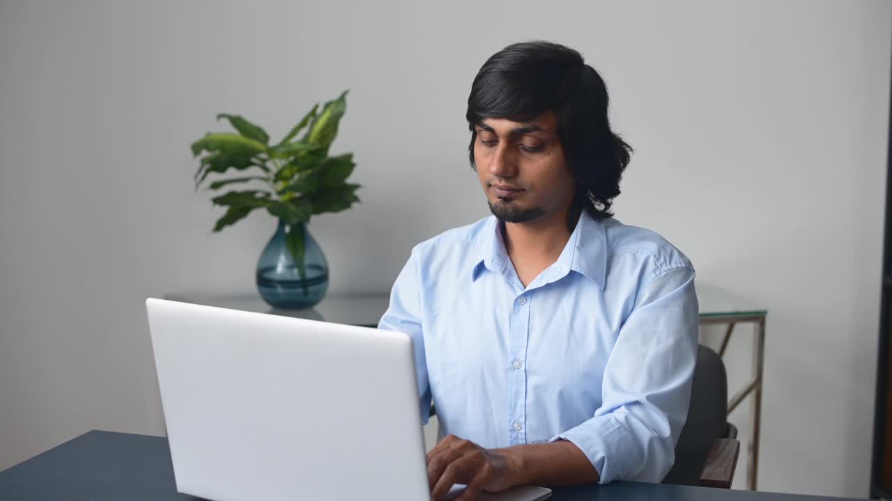 幸运的印度商人穿着休闲衬衫看着笔记本电脑的屏幕视频素材