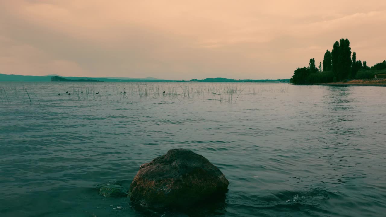 在意大利托斯卡纳的一个小湖中，海浪拍打着岩石。视频素材