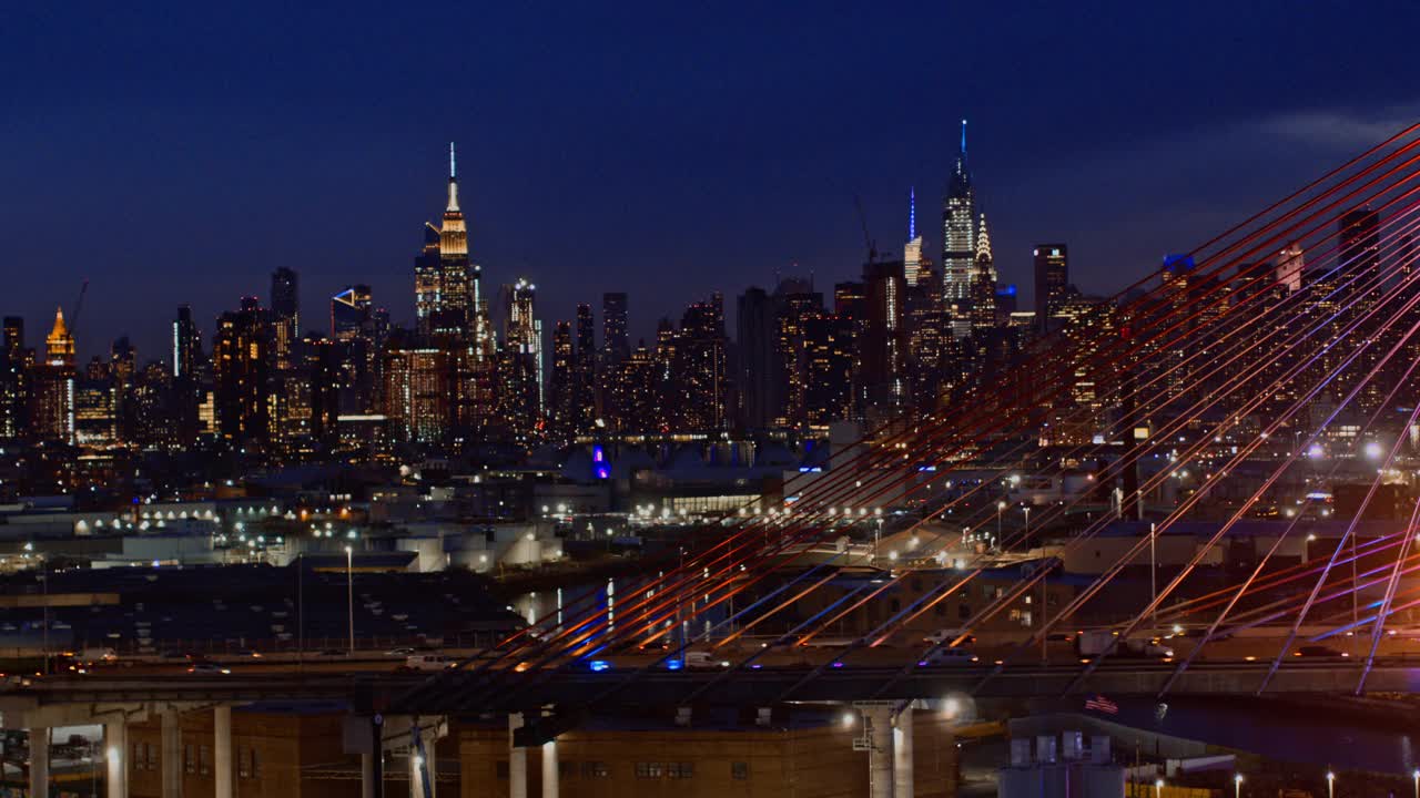 在灯火通明的科修斯科大桥上，曼哈顿中城天际线的夜景。航拍视频与快速平移摄像机运动。视频下载