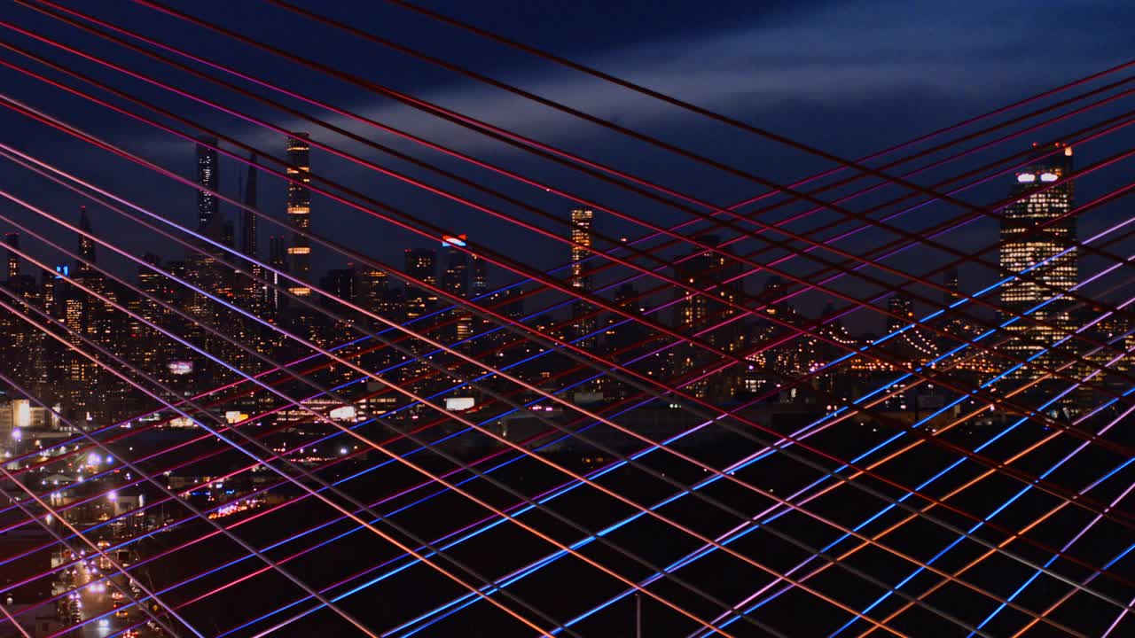 在灯火通明的科修斯科大桥上，曼哈顿中城天际线的夜景。航拍视频与平移摄像机运动。视频下载