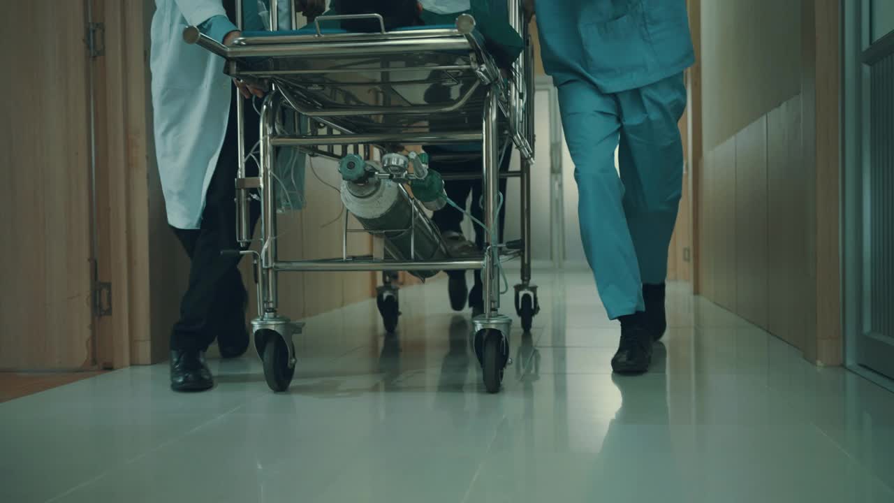 从低角度看，医疗组正把躺在床上的病人从走廊推到手术室。视频下载