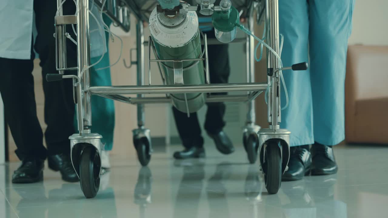 从低角度看，医疗组正把躺在床上的病人从走廊推到手术室。视频素材