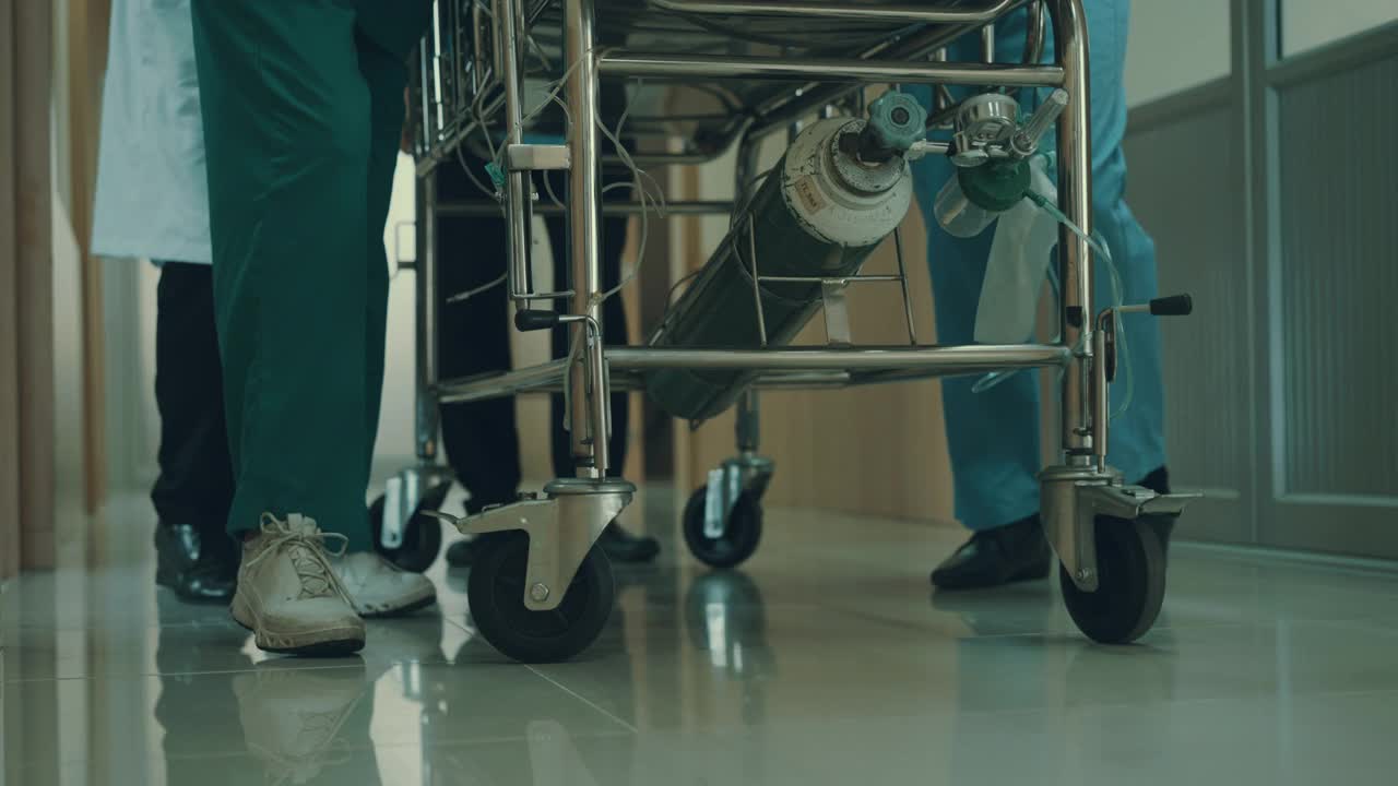 从低角度看，医疗组正把躺在床上的病人从走廊推到手术室。视频素材