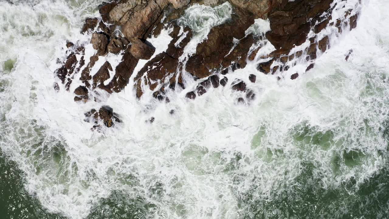 无人机飞过海浪拍打岩石的上空视频素材