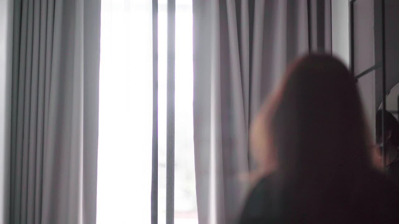 亚洲女人在酒店房间拉开窗帘视频素材