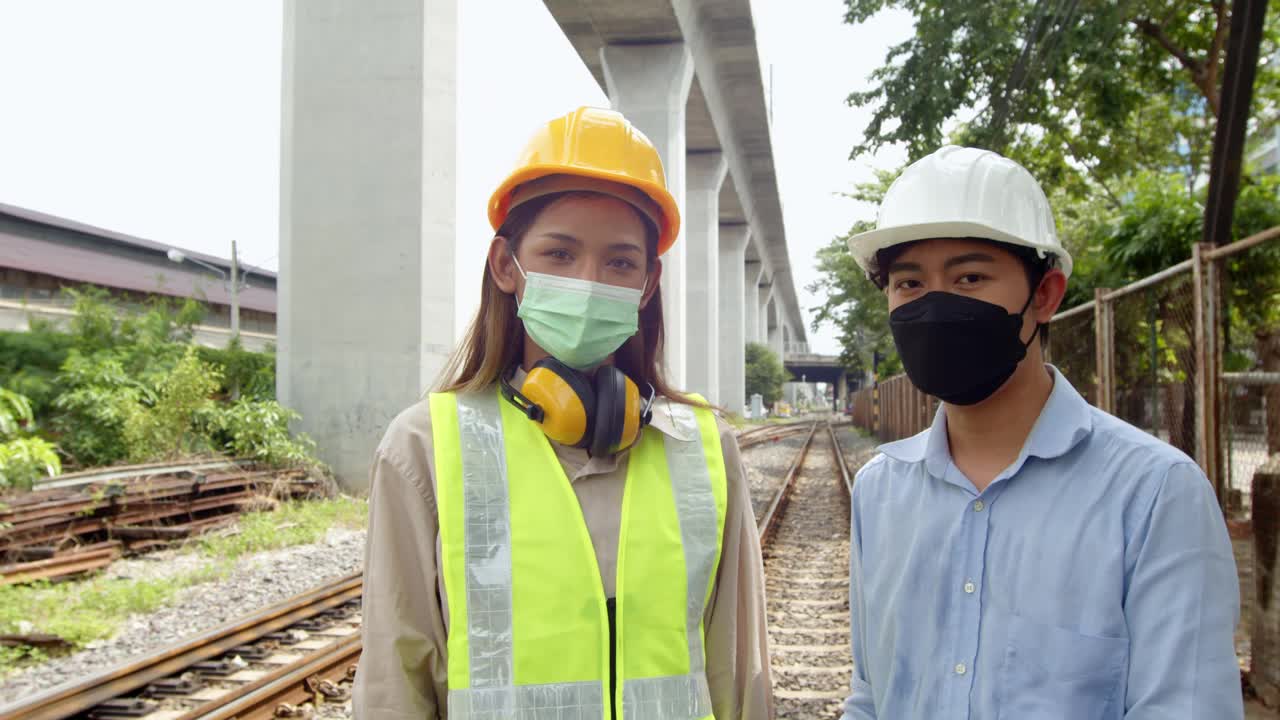 两名男工程师和女检查员摘下安全帽、防护面罩并微笑视频下载
