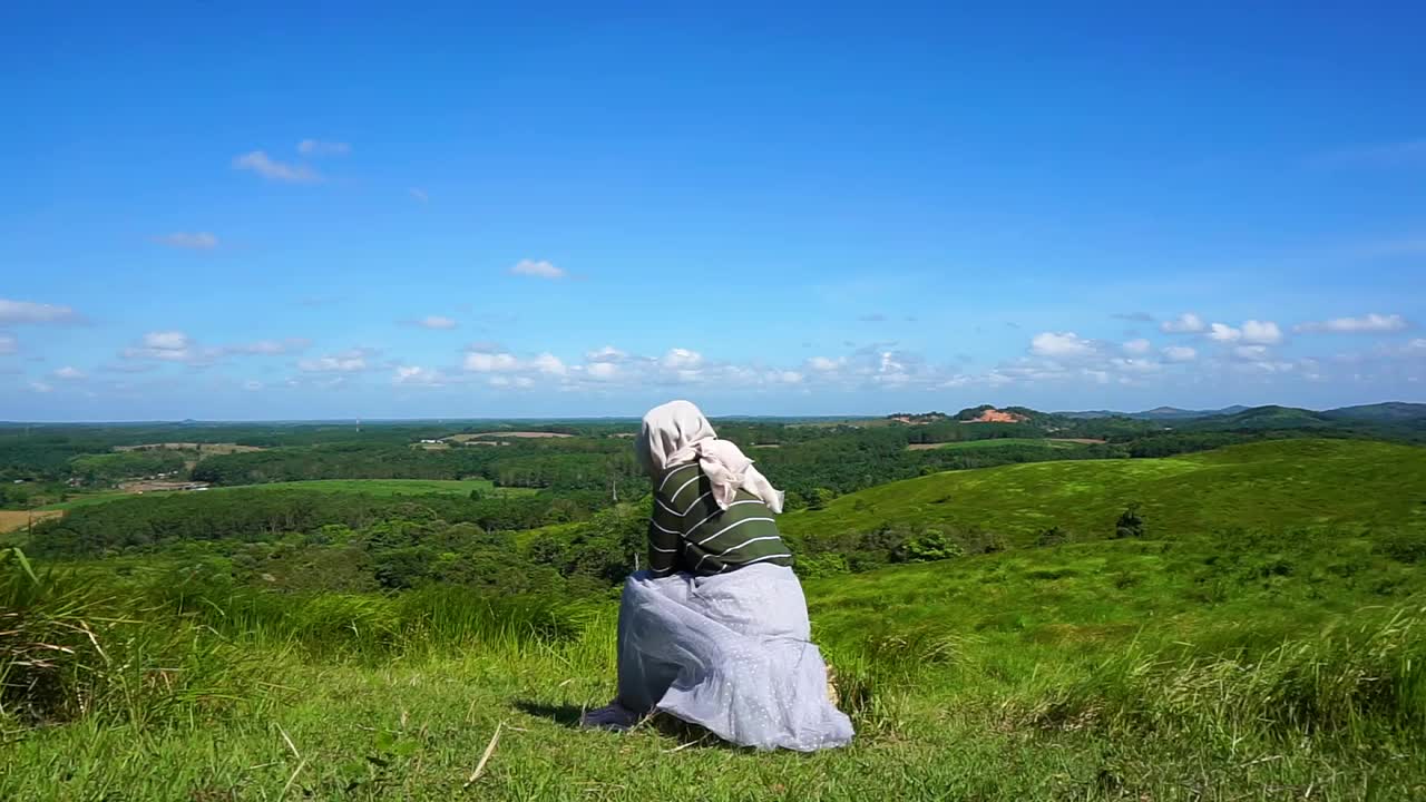 年轻的女人坐在山顶上，自由，放松视频下载