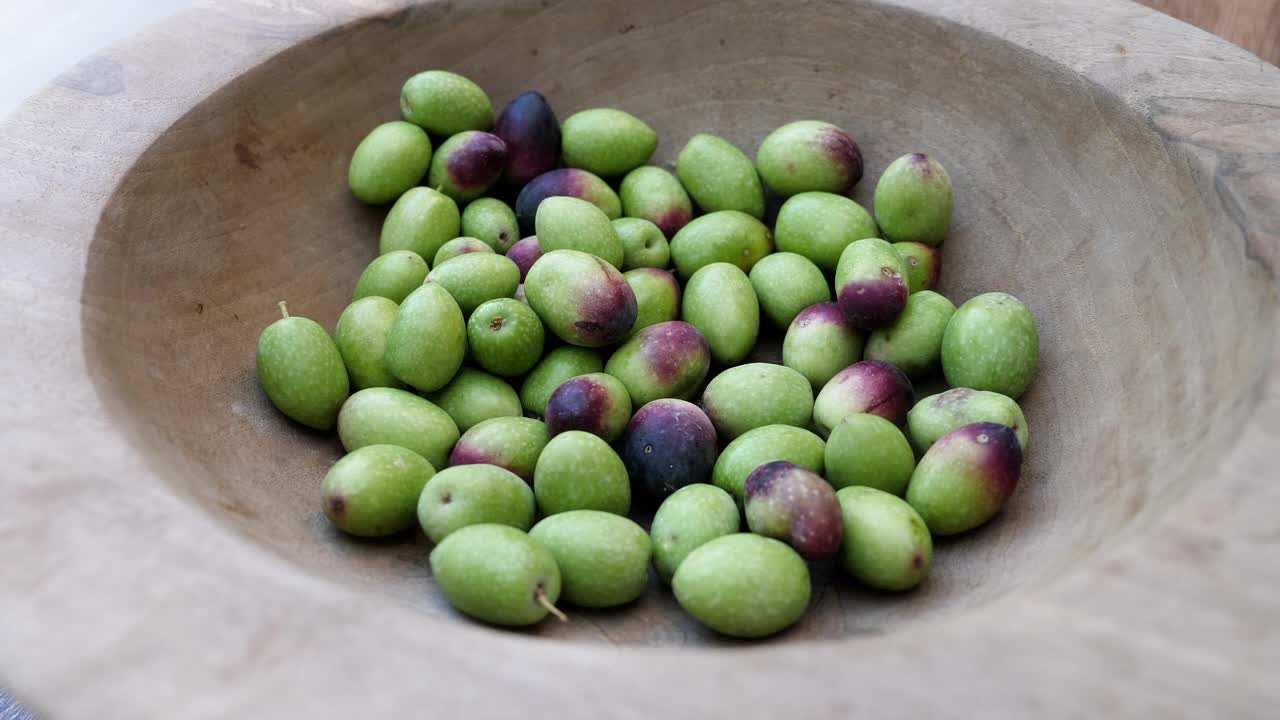 绿色的摩洛哥橄榄被倒进一个木碗里。收获橄榄。视频下载