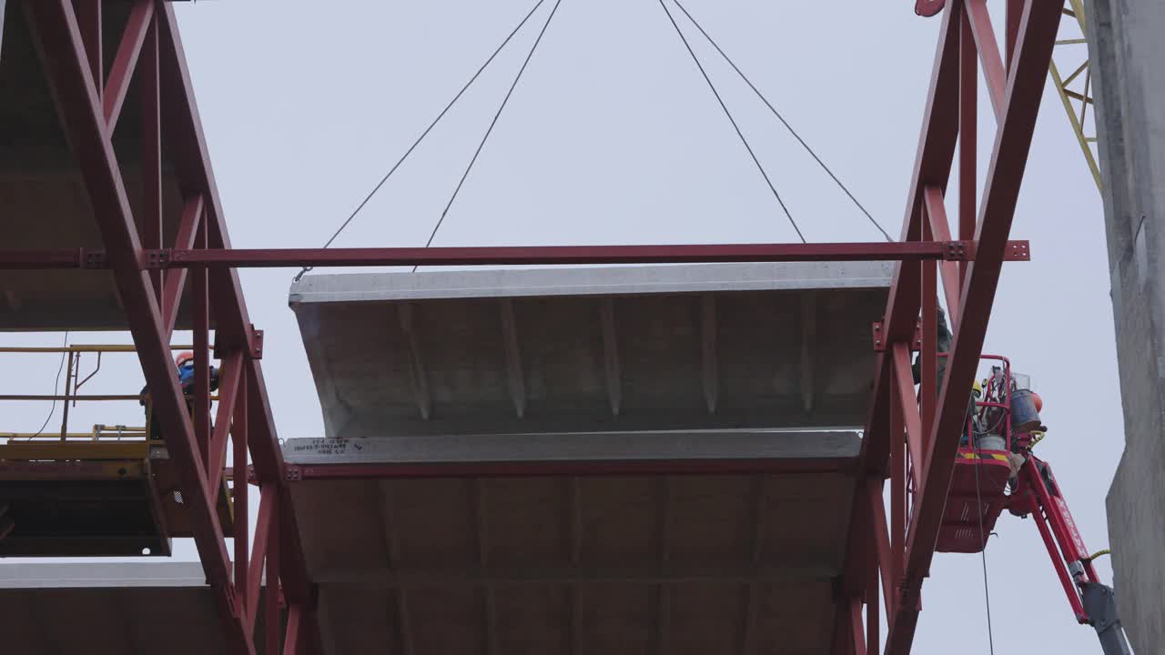 工人们正在用起重机将钢筋混凝土板安装在建筑物的屋顶上视频下载