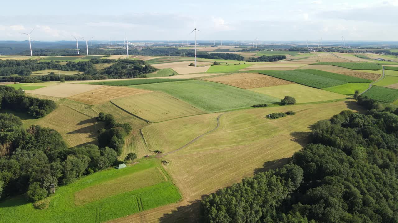 飞越绿色和黄色的田野，飞向风力涡轮机农场视频素材