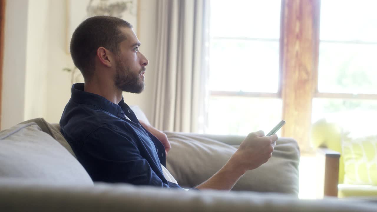 男人坐在家里的沙发上看电视视频素材