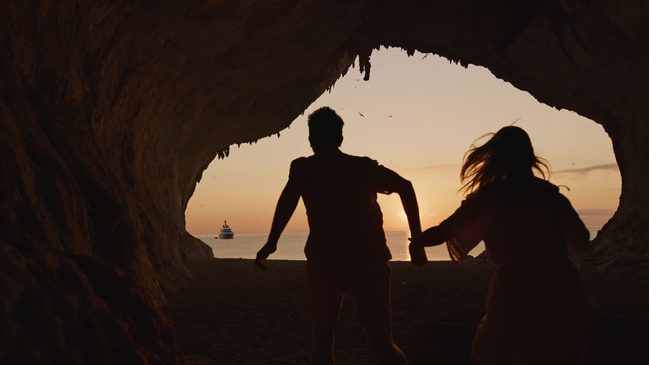慢动作的观点，一对夫妇在沙滩上跑步，cala Luna，撒丁岛，意大利。视频下载