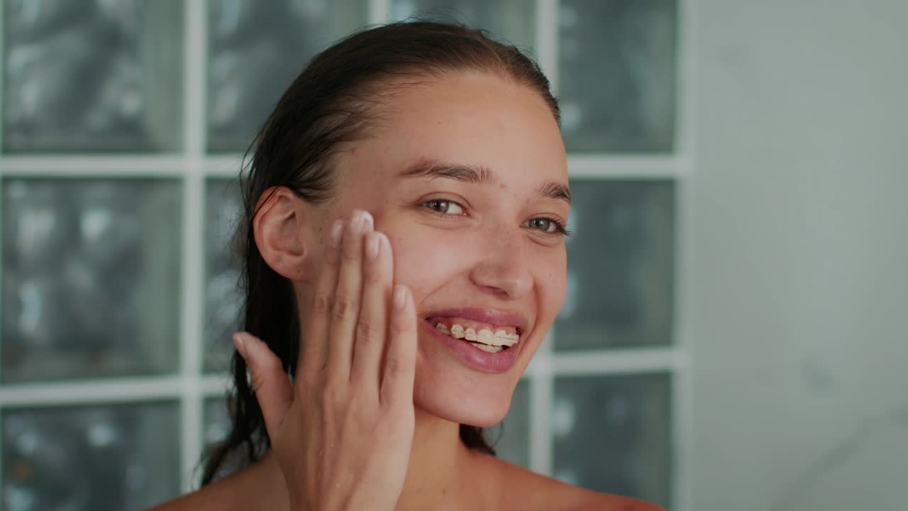 快乐女人在浴室用保湿霜护肤视频下载