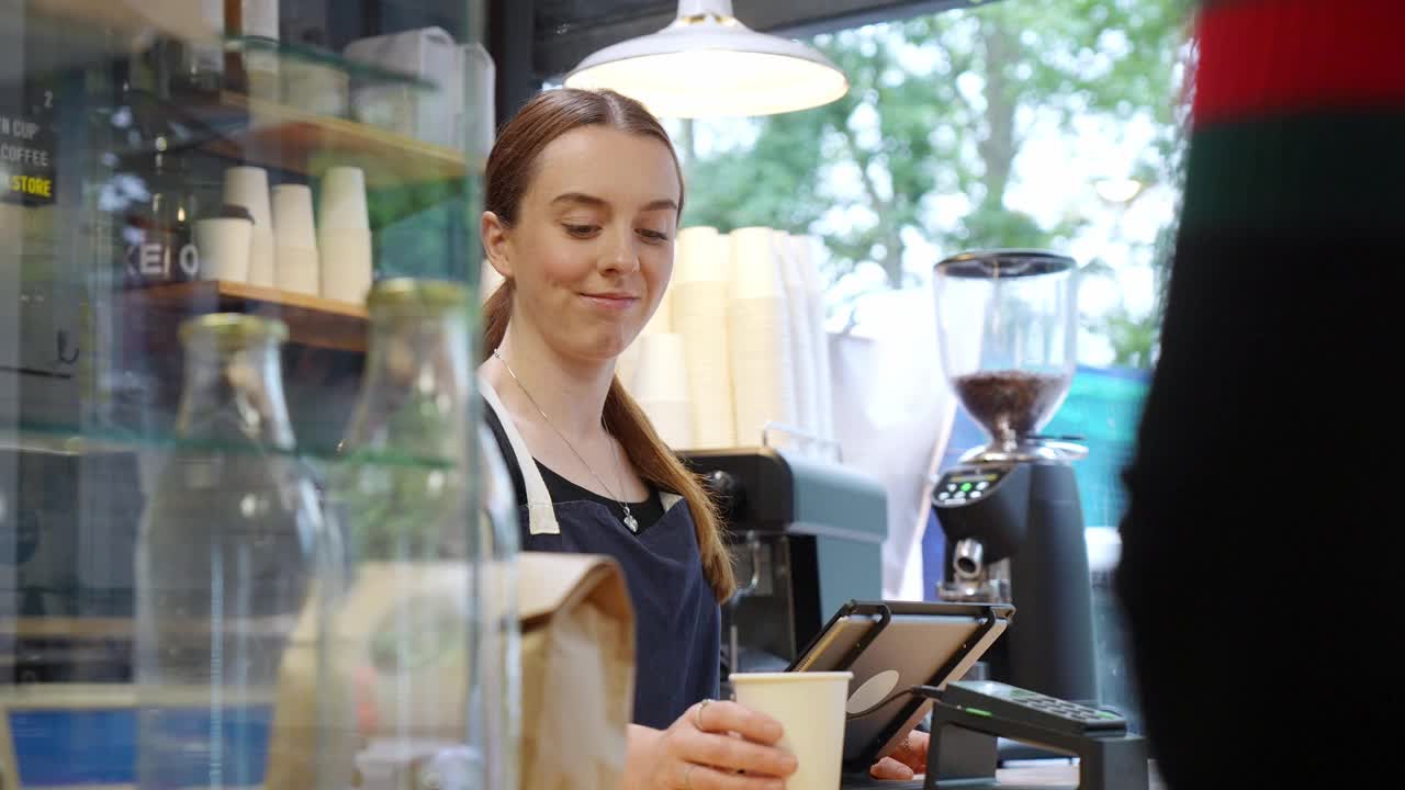 年轻的店主在咖啡馆里给顾客端咖啡视频下载