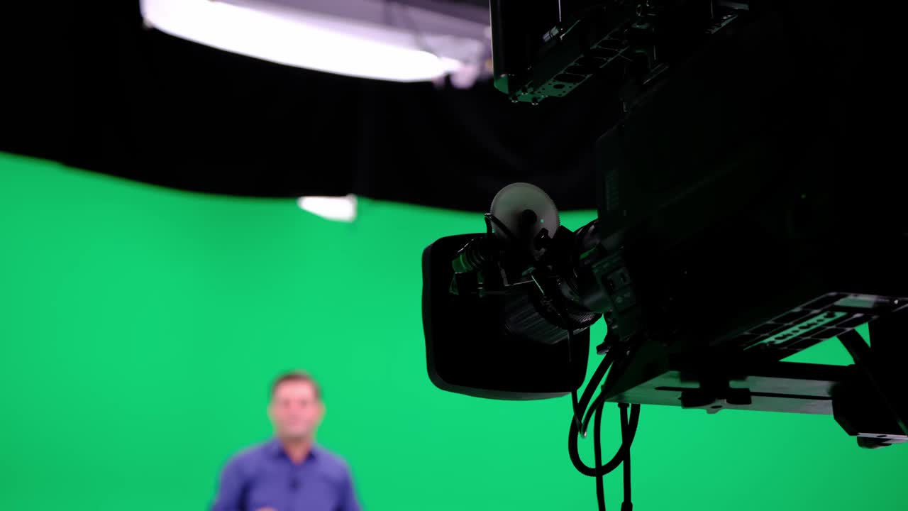 电影摄制组在绿色摄影棚拍摄录像。色度-在单一构图中结合两个或多个图像或帧的技术。摄影师、导演、船员。电影制作行业。视频素材