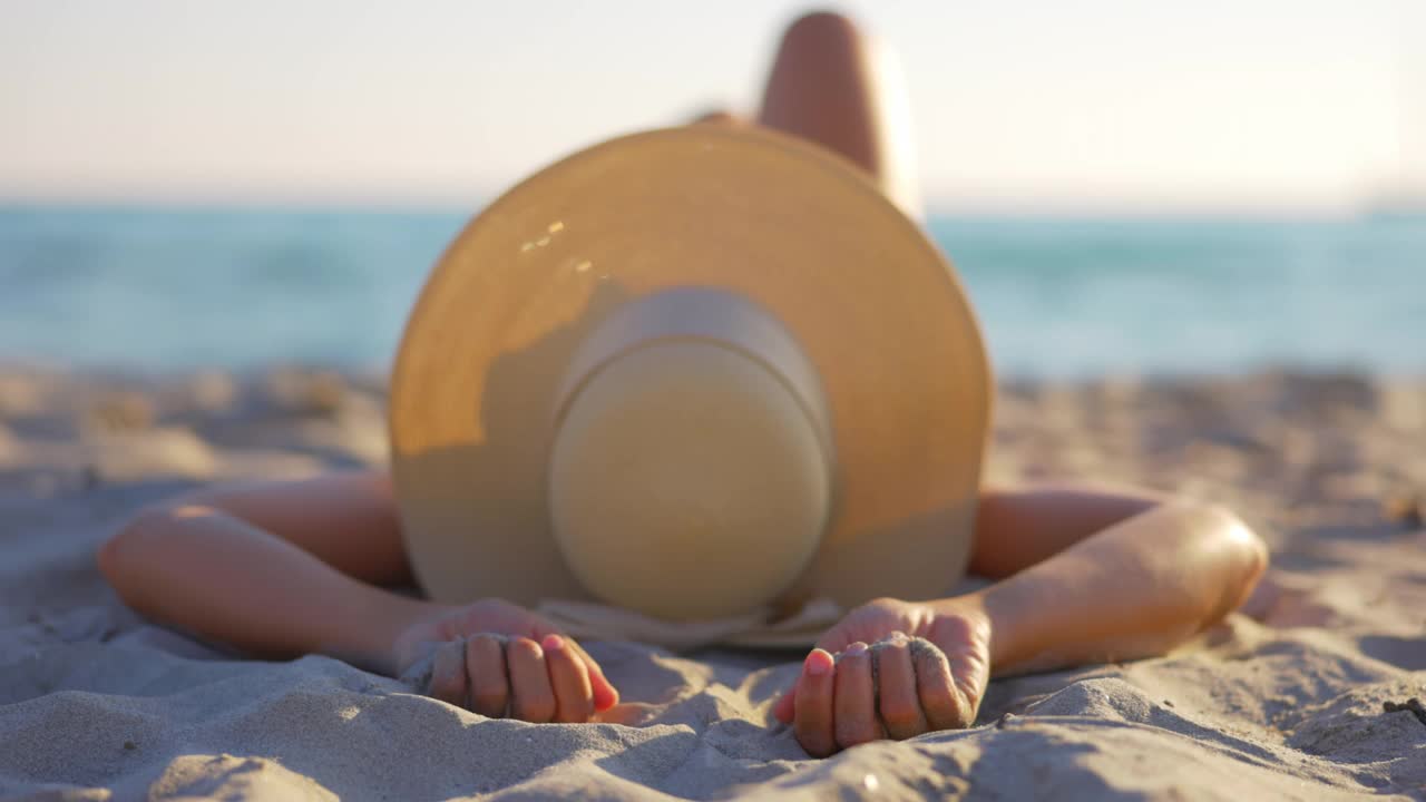 在撒丁岛海滩上一个带着帽子的女人的慢动作视图。视频下载