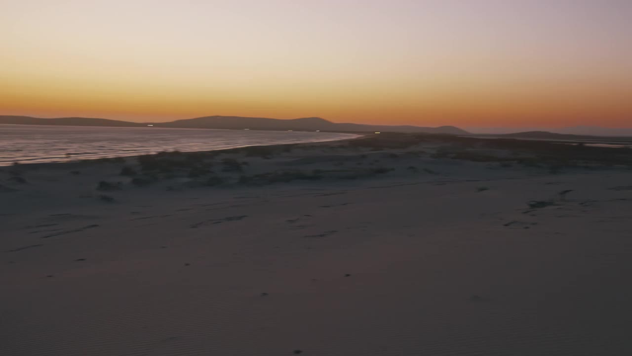 一个人在日落时在海滩上散步的慢动作视图。视频素材