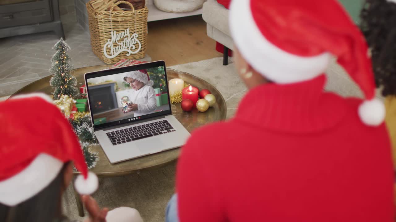 戴着圣诞帽的非洲裔美国家庭使用笔记本电脑与屏幕上的男孩进行圣诞视频通话视频下载