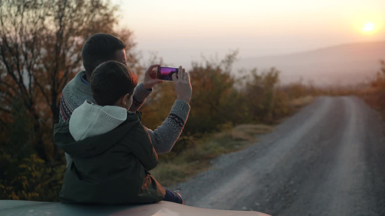 父亲和儿子在公路旅行时拍摄美丽的日落视频素材