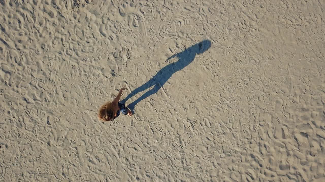 在沙地上按顺序做瑜伽的女人的无人机视图视频下载