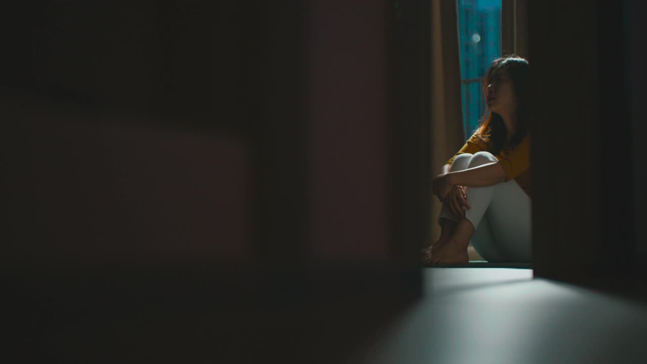 一个抑郁的女人独自坐在公寓房间的地板上视频素材